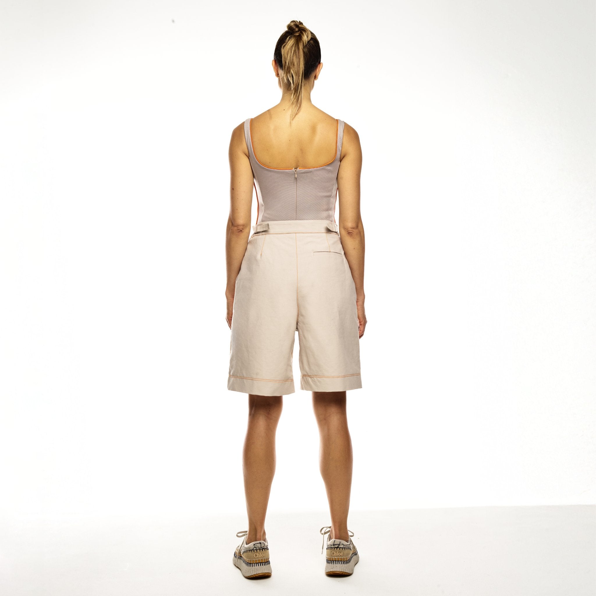 Woman wearing beige bermudas white background