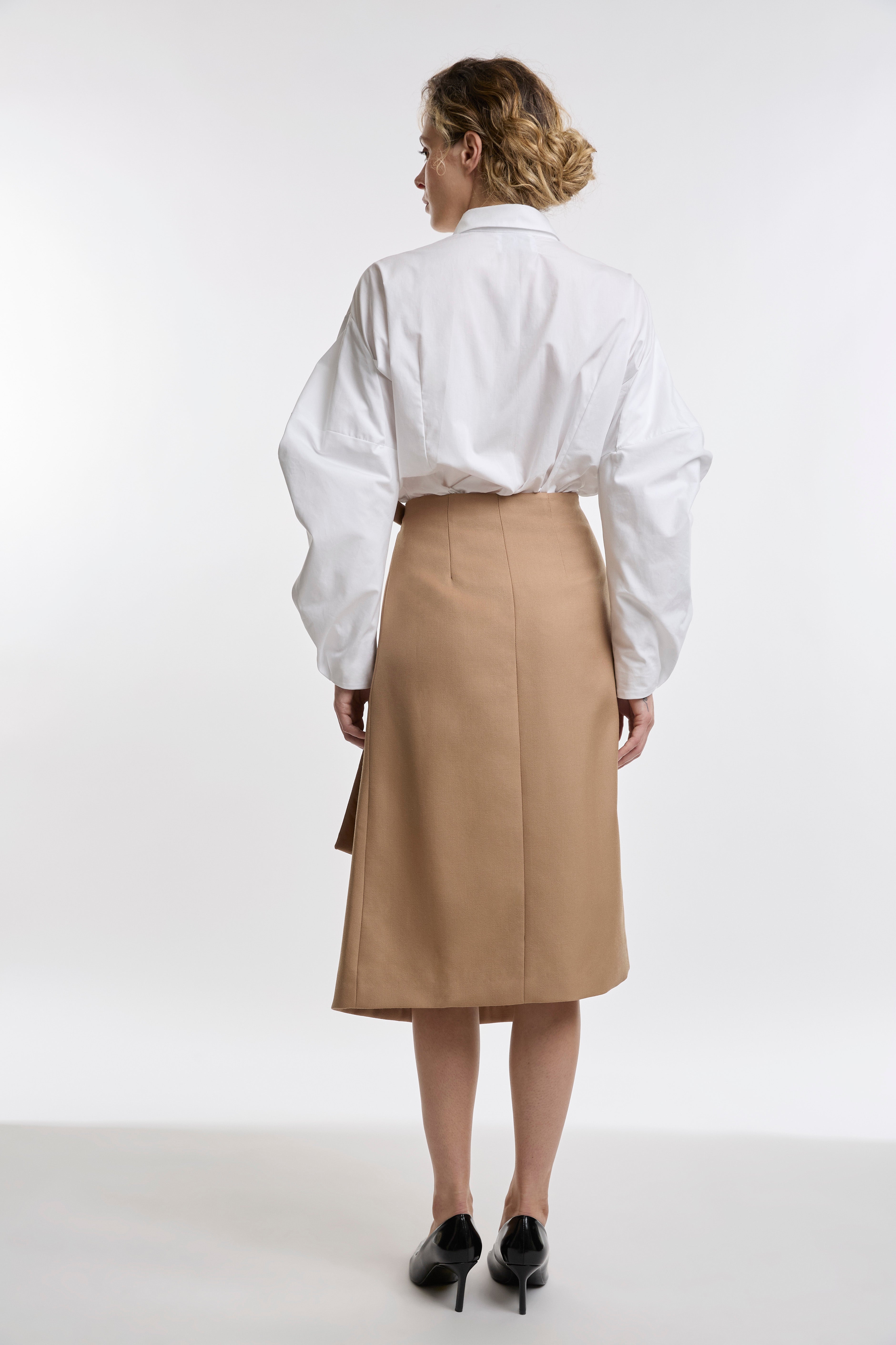 Person wearing a white shirt and camel skirt on a white background