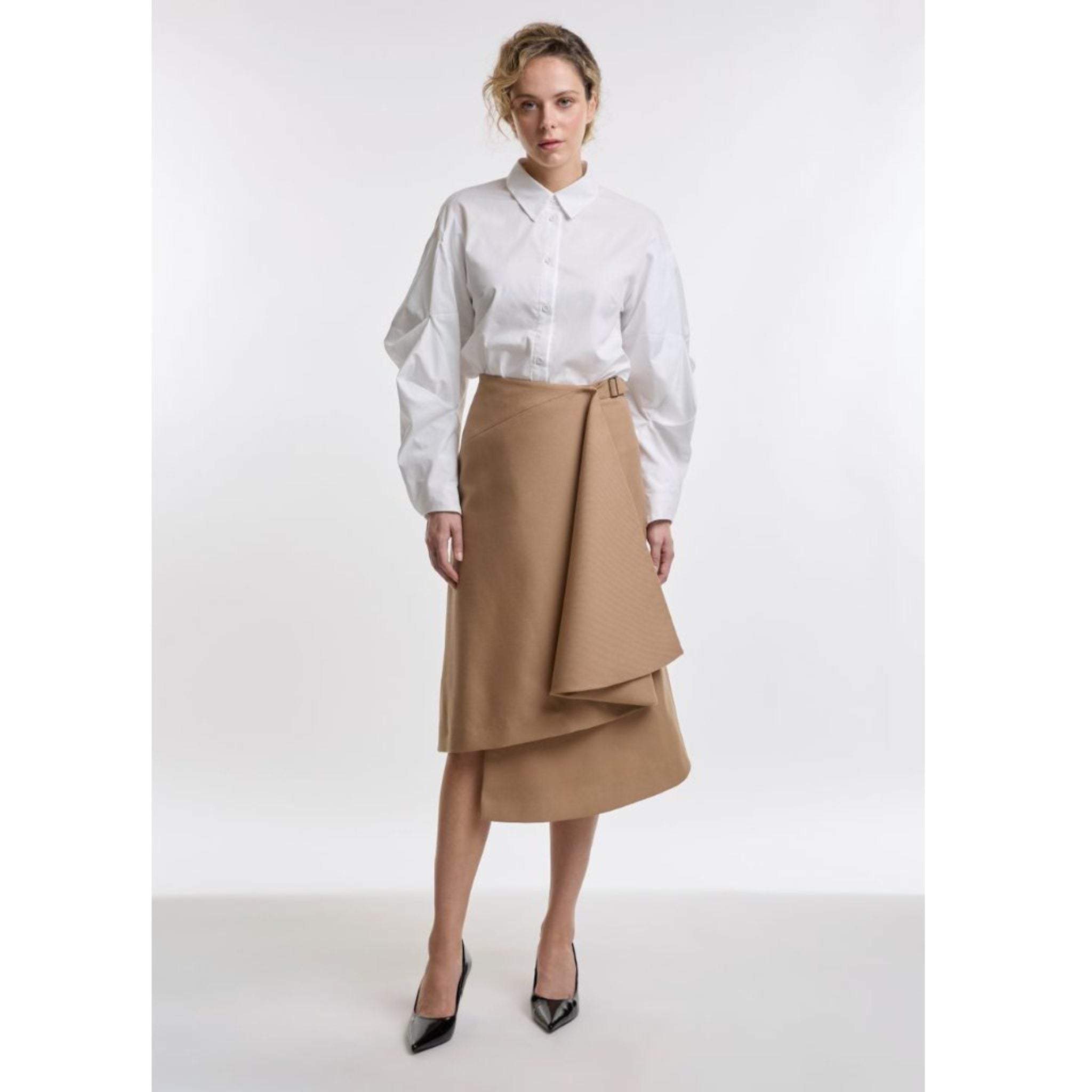 Woman wearing a white blouse and camel skirt on a white background