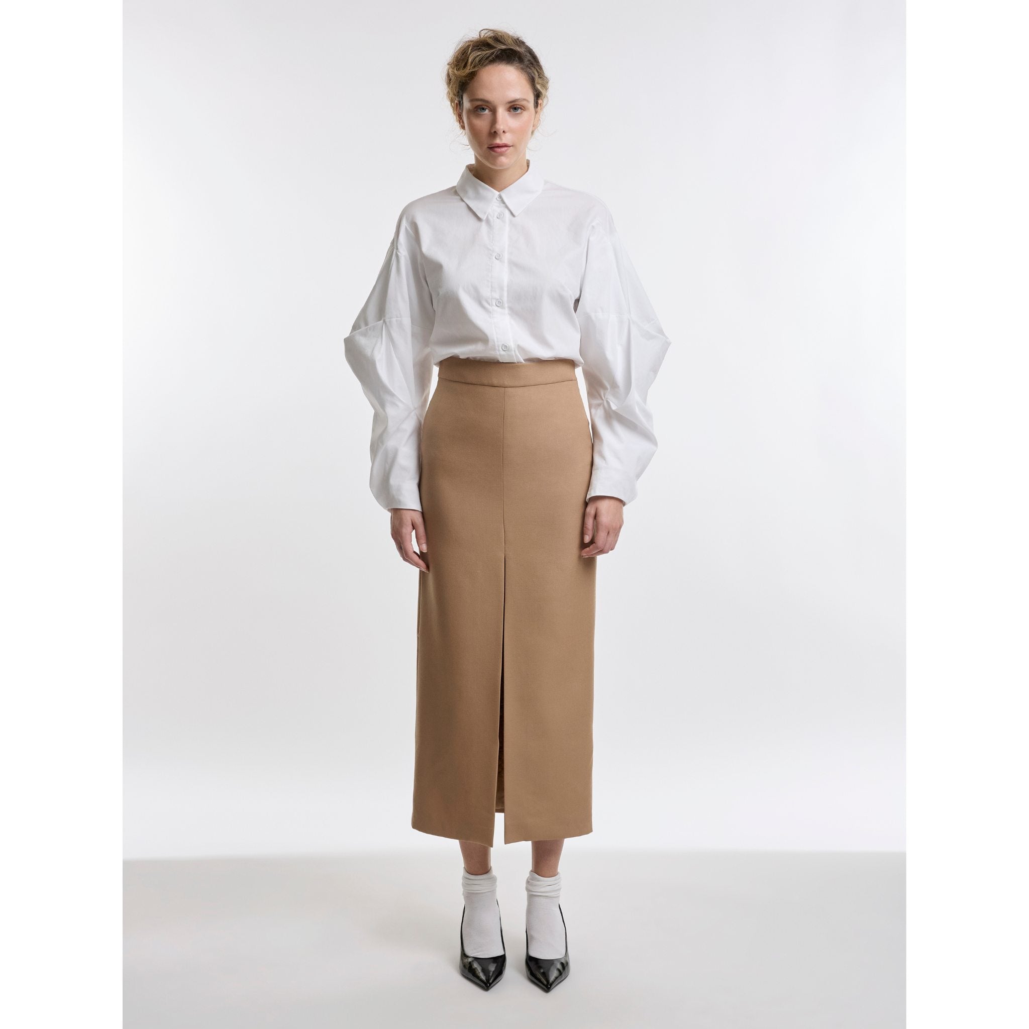 Woman wearing a white blouse and beige skirt on a white background