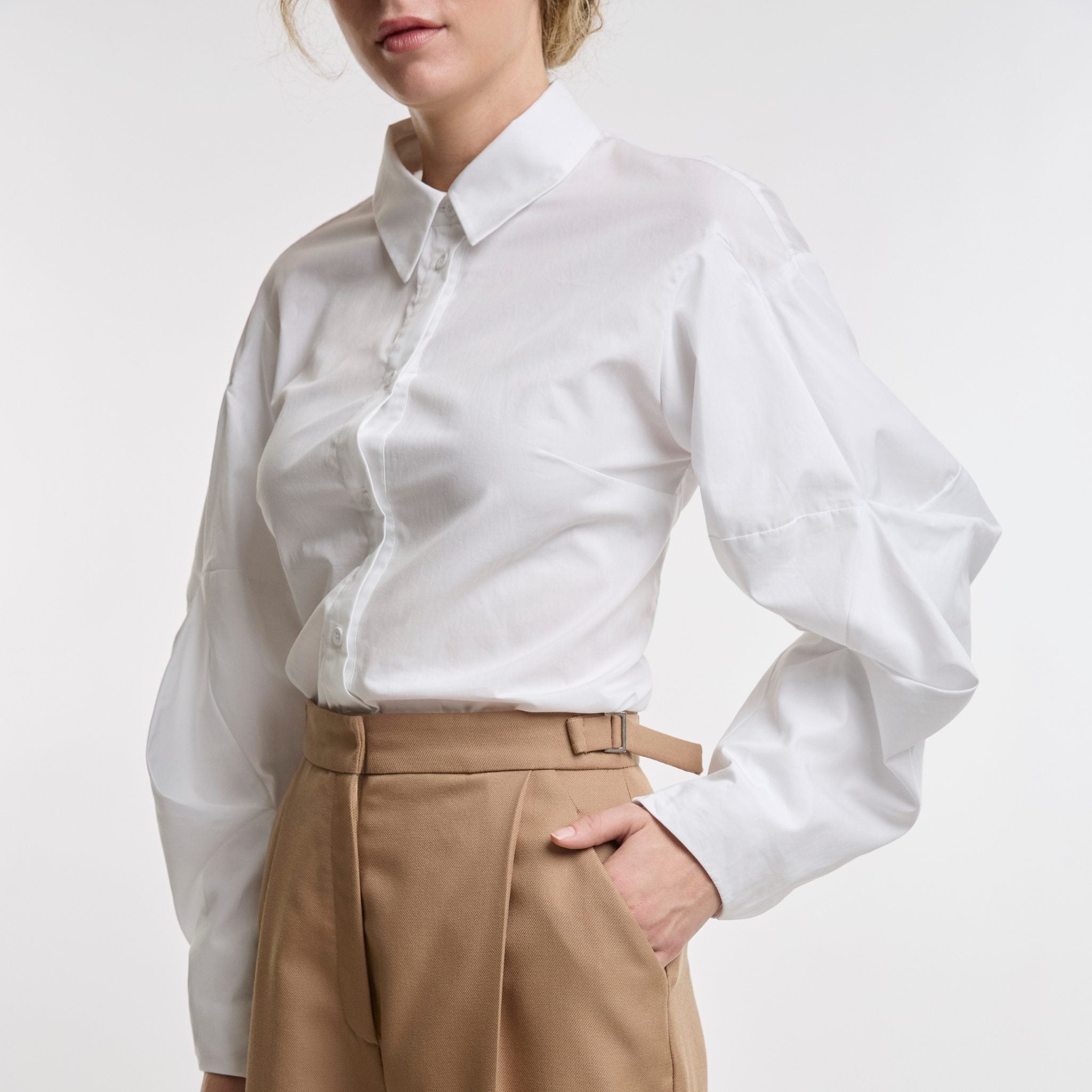 woman wearing a white shirt and camel trousers