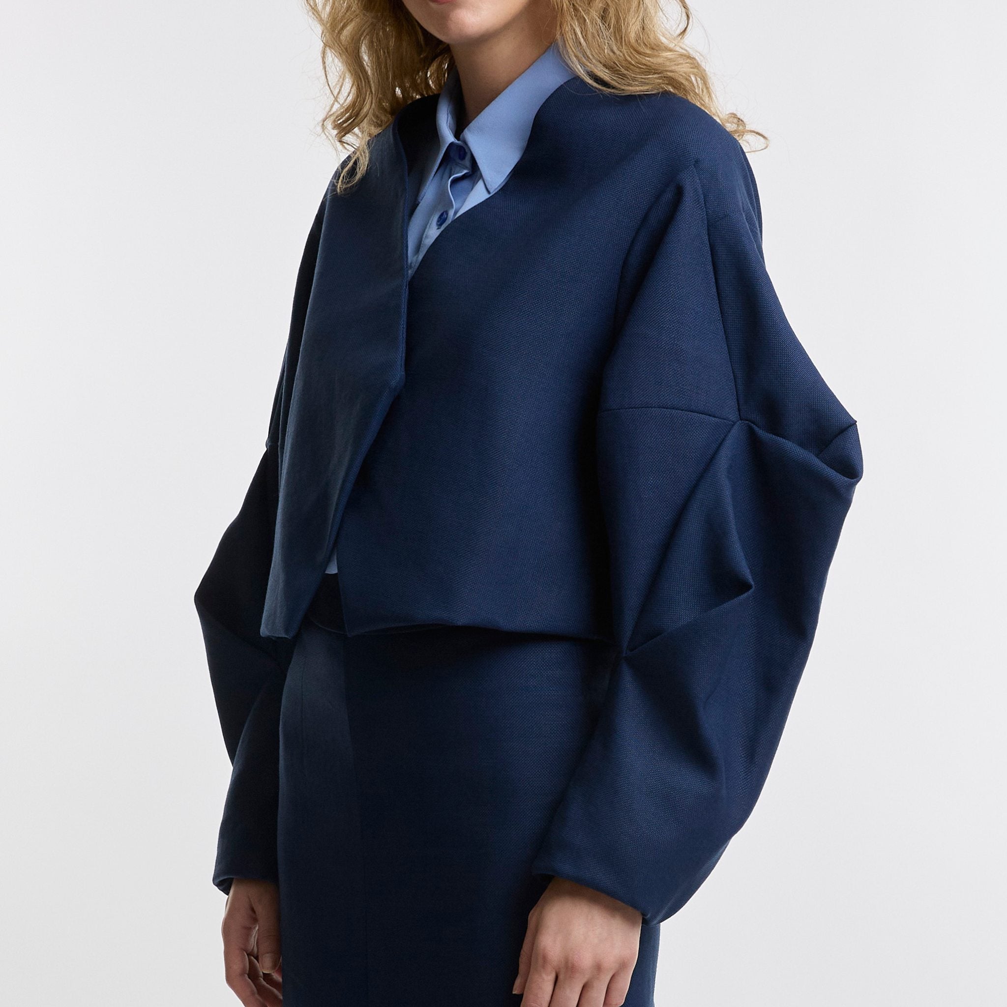 woman wears cropped jacket on white background