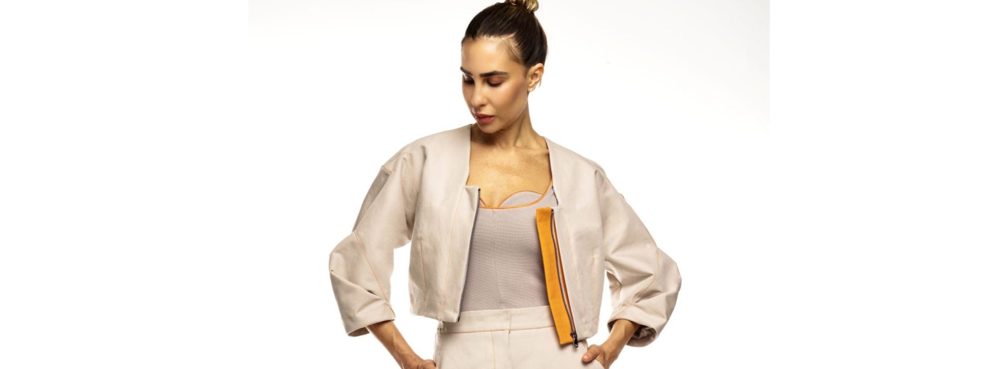 Woman wearing a beige jacket and white pants on a white background