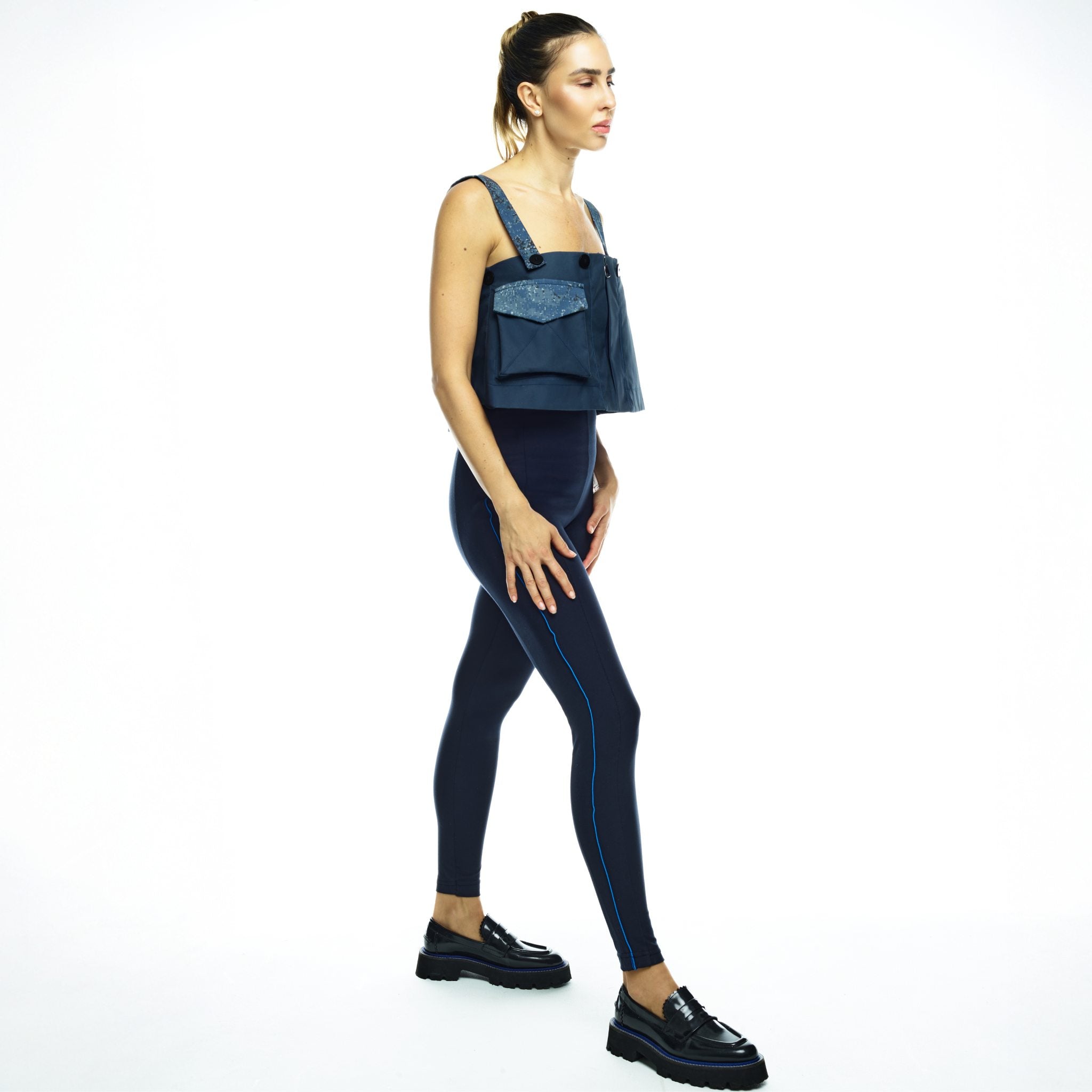 Woman wearing a crop top and navy jumpsuit on a white background