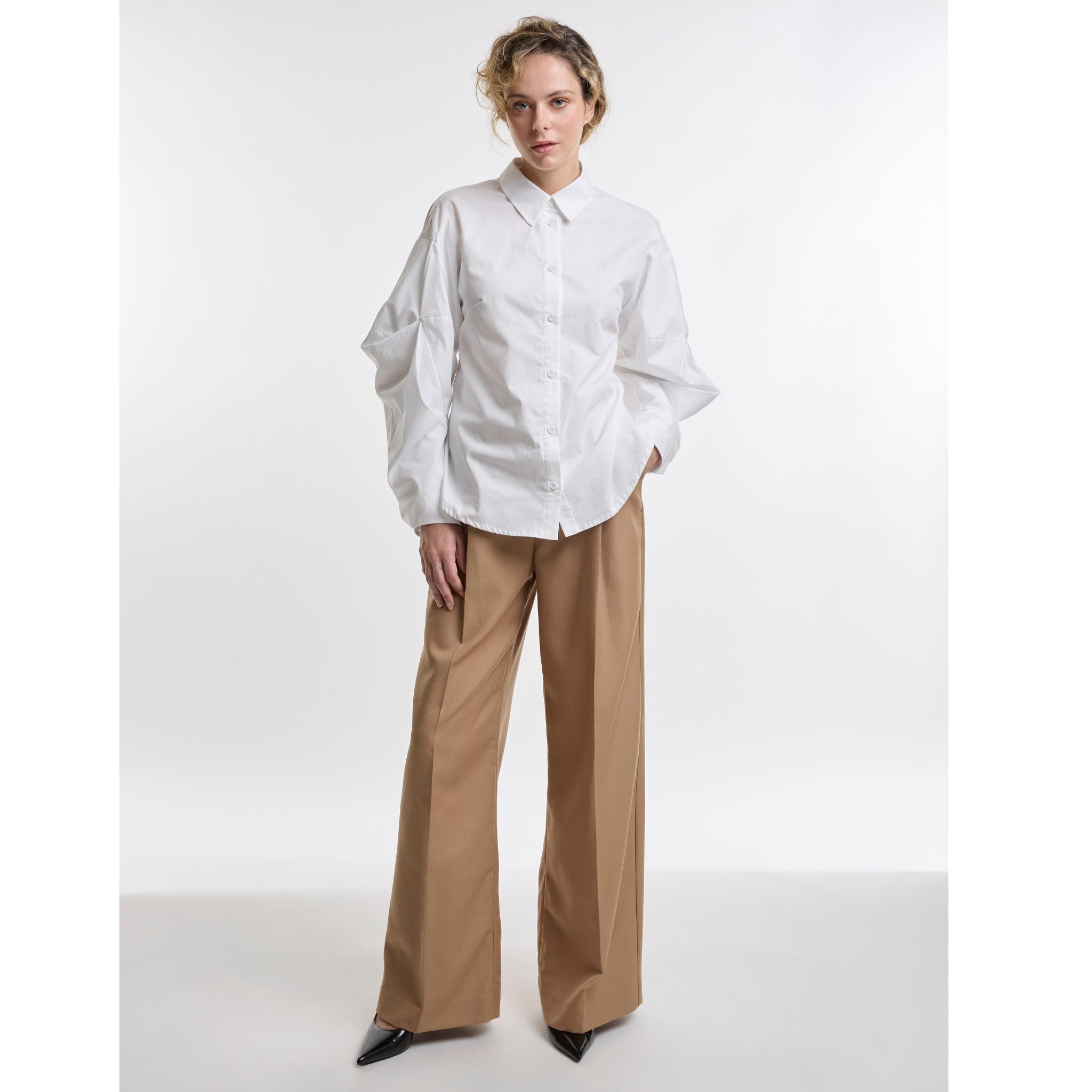 woman wearing a shirt and camel trousers
