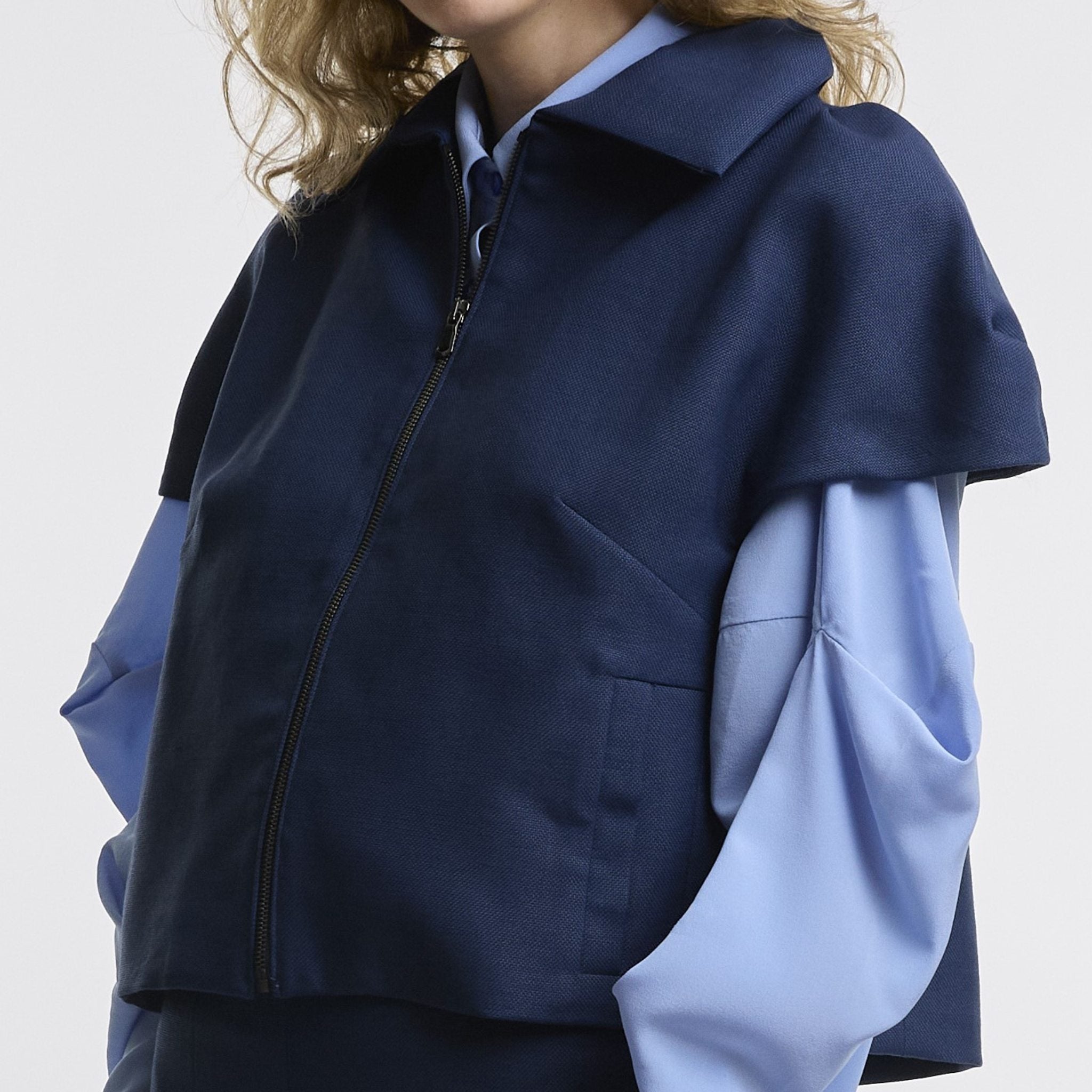 Person wearing a blue jacket over a light blue shirt on a white background